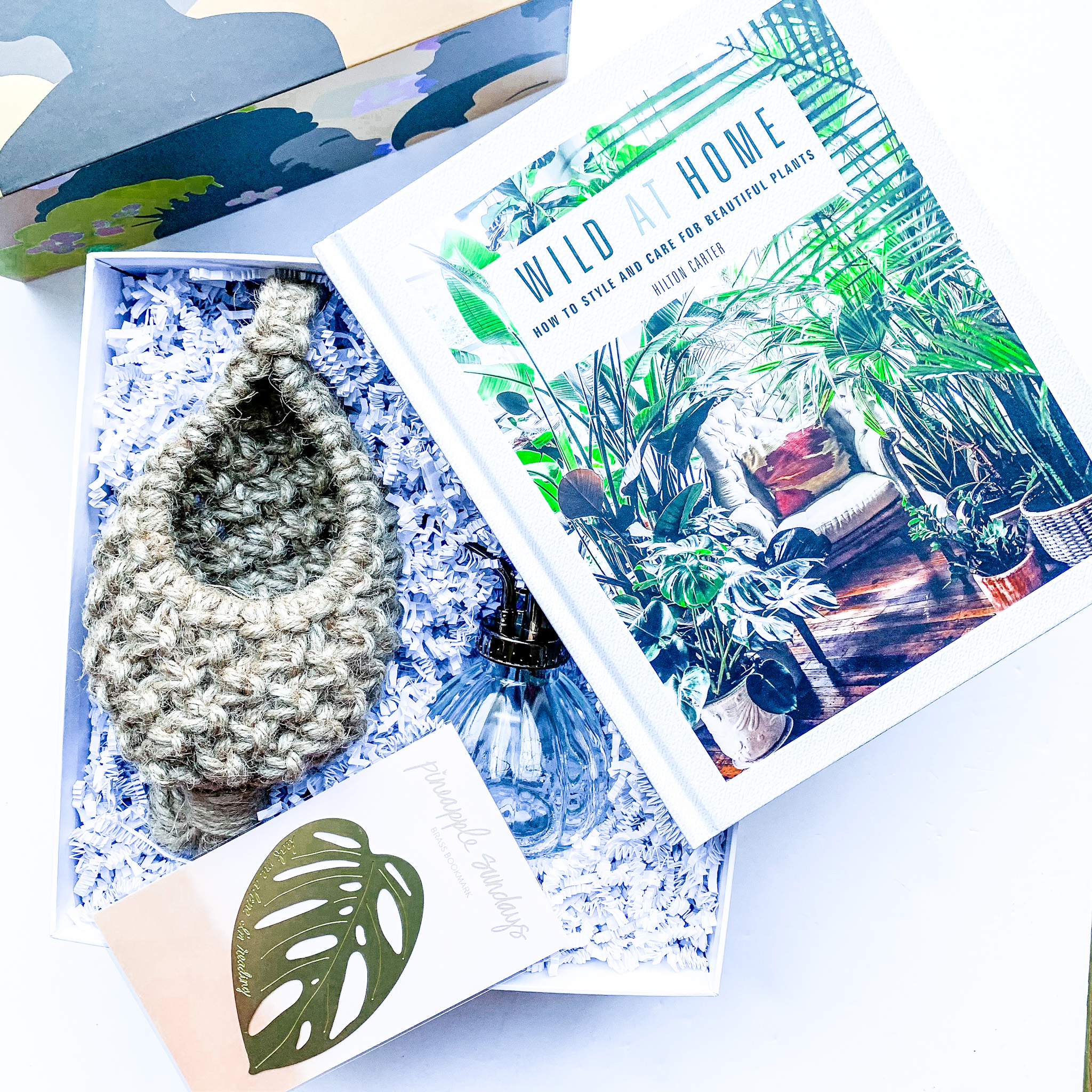 A gift box including items on plant care, including a book, a spray bottle, and a card.